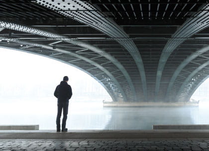 Man walking under bridge